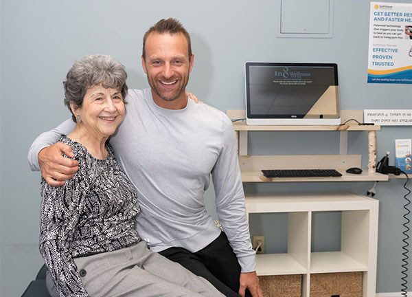 Dr. Hewitt with his arm around an aging chiropractic patient